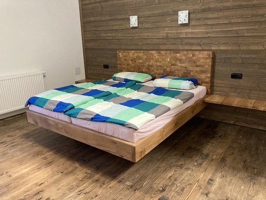 Dubová postel  čelo složené příčně v pozadí dřevěná stěna